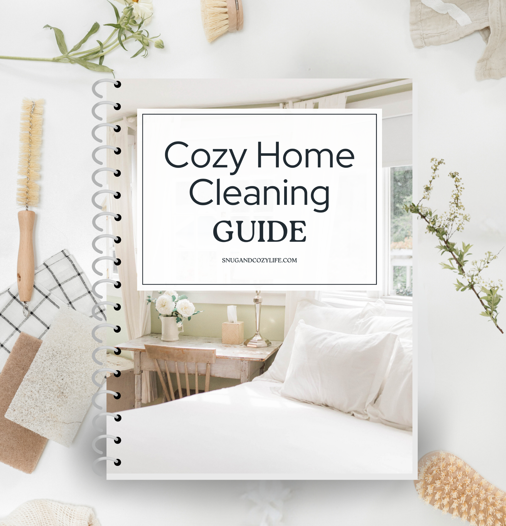 this is a mockup of our cozy home cleaning guide on a binder. there are cleaning brushes, sponges, rags, and sprigs of flowers surrounding it on the table.
