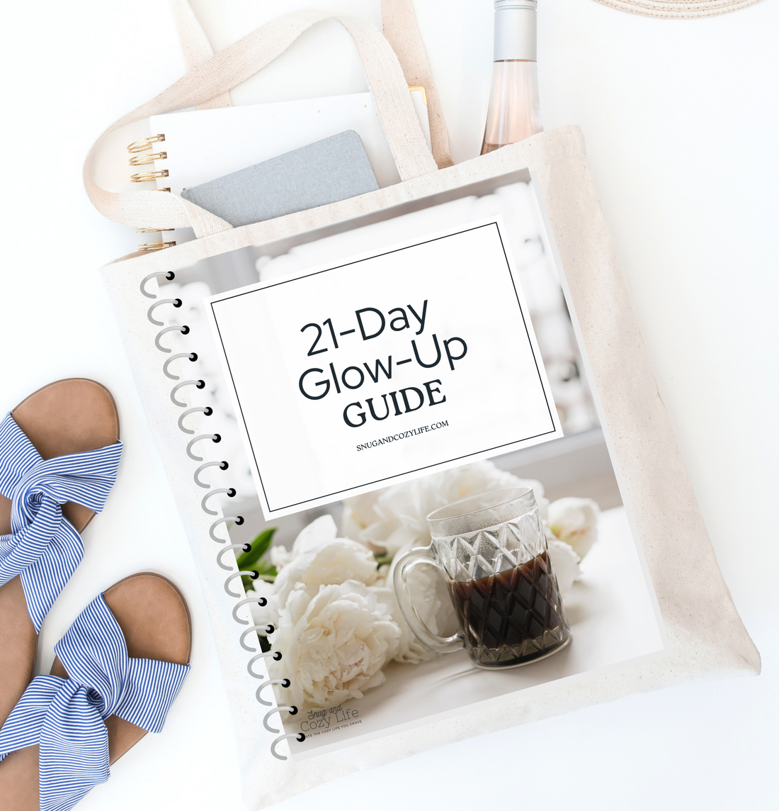This is a mockup of our 21-day glow-up guide as a binder. It sits on top of a tote bag filled with a tablet and wine bottle on a table with a pair of shoes.