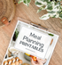 This is a mockup of our Family Meal Planning Printables on a clipboard on a table with a plant in the background.