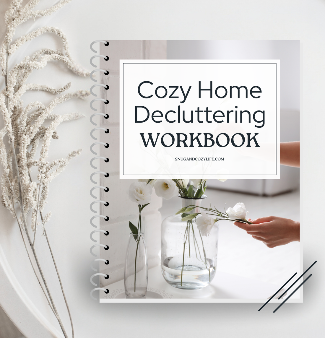 This is a mockup of our cozy home decluttering workbook in a binder on a table with sprigs of flowers on the left hand side.
